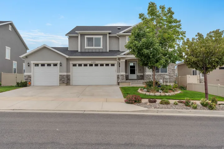 Two-story home featuring a light gray and stone exterior with dual two-car garages