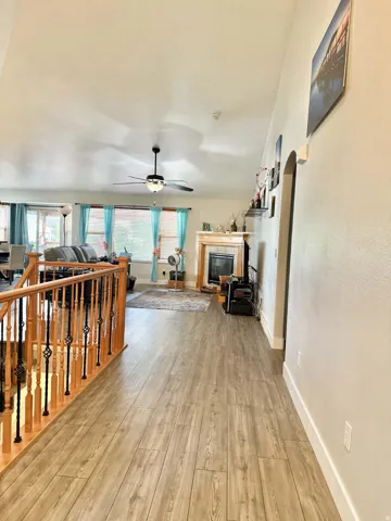 Vaulted ceilings, wood-finish flooring, wood staircase with iron balusters, and a fireplace with a wood mantel