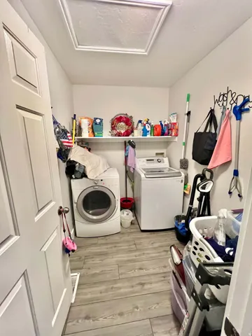 Laundry area featuring wood-finish flooring, a built-in wall shelf, and panel-style door