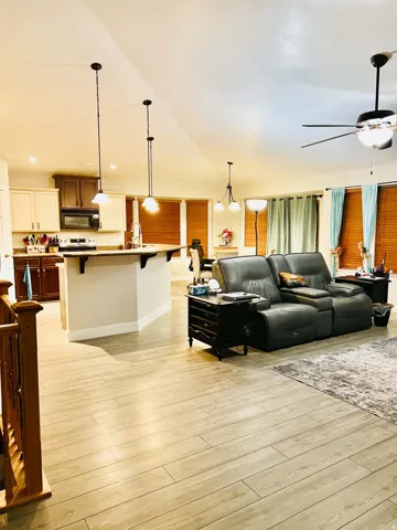 Expansive open-concept living space with vaulted ceilings, recessed lighting, and wood-finish flooring