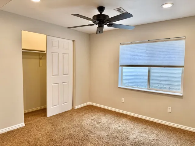 Recessed ceiling lighting, ceiling fan, window with privacy blind, closet with bi-fold door, and textured carpeting