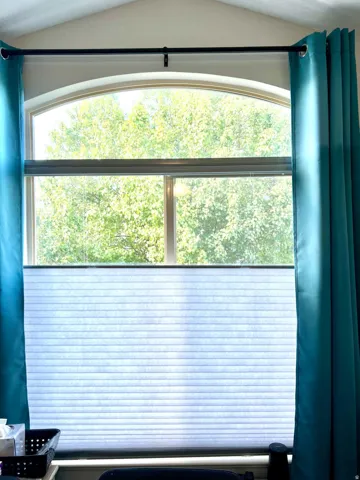 Arched window with upper transom, adjustable cellular shade, and high ceilings