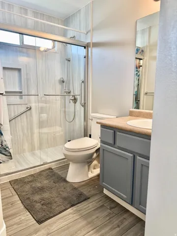 Glass-enclosed shower with a recessed shelf and grab bars