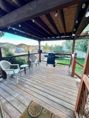 Covered wood deck with string lighting and wood railings