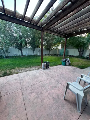 Expansive backyard featuring a wood pergola, stamped concrete patio, and a manicured lawn