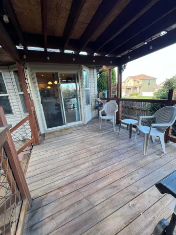 Wood deck with overhead covering and string lighting, featuring a sliding glass door