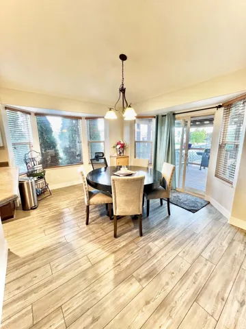 Bay window with horizontal blinds, wood-finish flooring, and a sliding glass door to the exterior