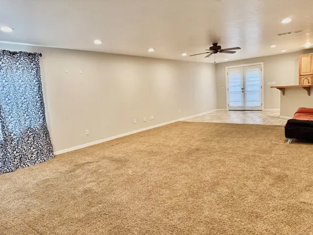 Recessed lighting, ceiling fan, neutral wall colors, light wood-finish cabinetry, and double French doors