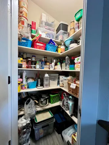Corner pantry with multiple built-in shelves and wood-finish flooring