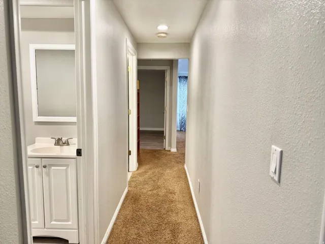Hallway featuring textured walls and carpet flooring