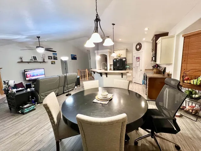 Vaulted ceilings, wood-finish flooring, kitchen with peninsula, recessed lighting, and ceiling fan with light