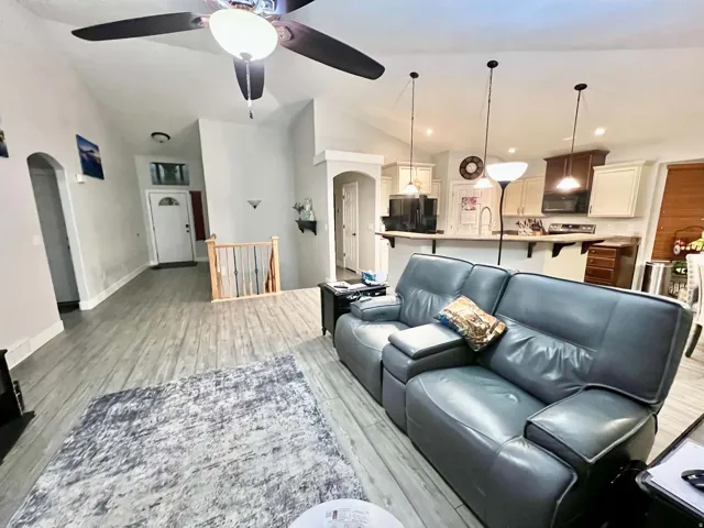Vaulted ceilings with a ceiling fan, recessed lighting, wood-finish flooring, and a kitchen featuring pendant lighting and built-in cabinetry