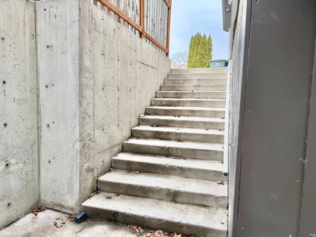 Concrete retaining wall and exterior staircase with a wooden fence