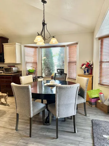Bay window with wood-finish blinds, complemented by a decorative chandelier
