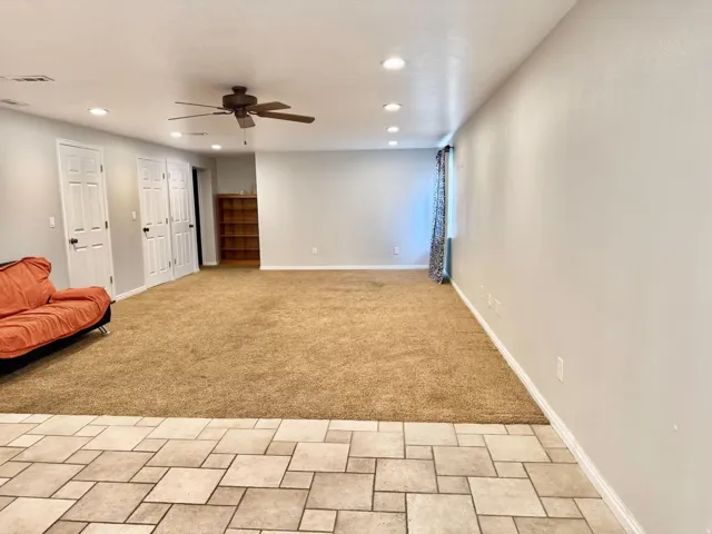 Spacious room with recessed lighting, ceiling fan, and mixed flooring of carpet and tile