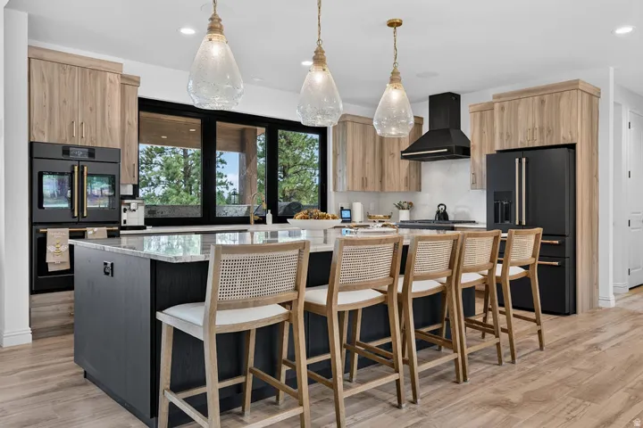 Gourmet kitchen with wood-finish flooring, two-tone cabinetry, built-in double ovens, and a large central island with seating