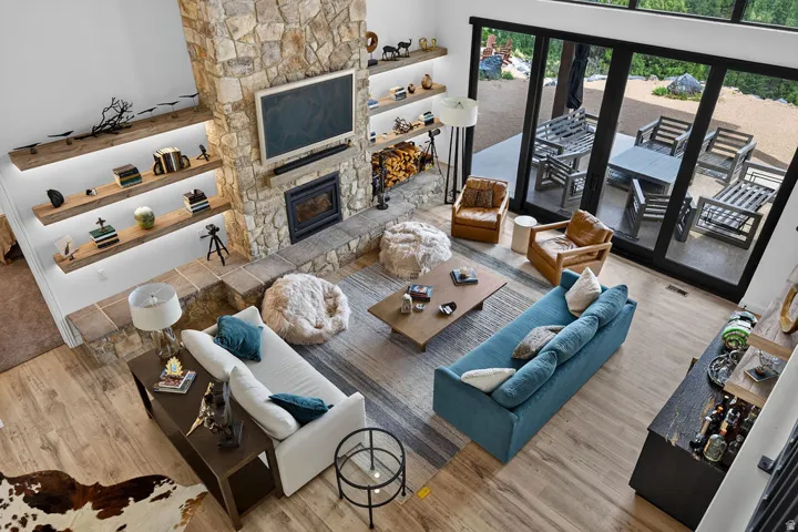 Open-concept living area featuring a stone-clad fireplace and wood-finish flooring