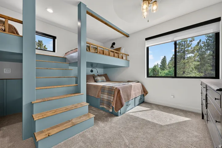 Built-in bunk beds with integrated stairs, under-bed storage drawers, a large window, recessed lighting, and a decorative ceiling fixture