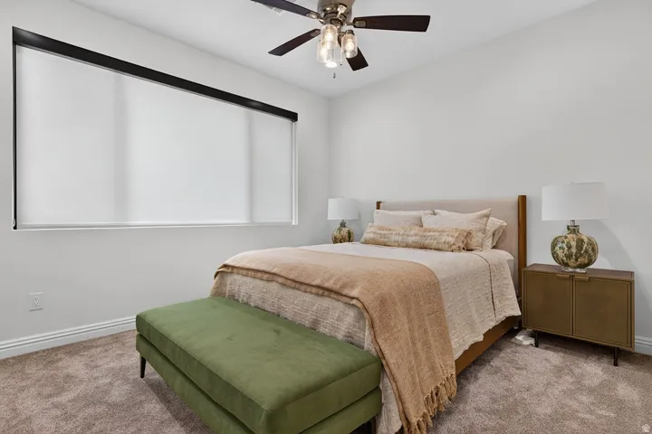 Recessed window with roller shade, ceiling fan with integrated lighting, wall-to-wall carpeting, and sloped ceiling