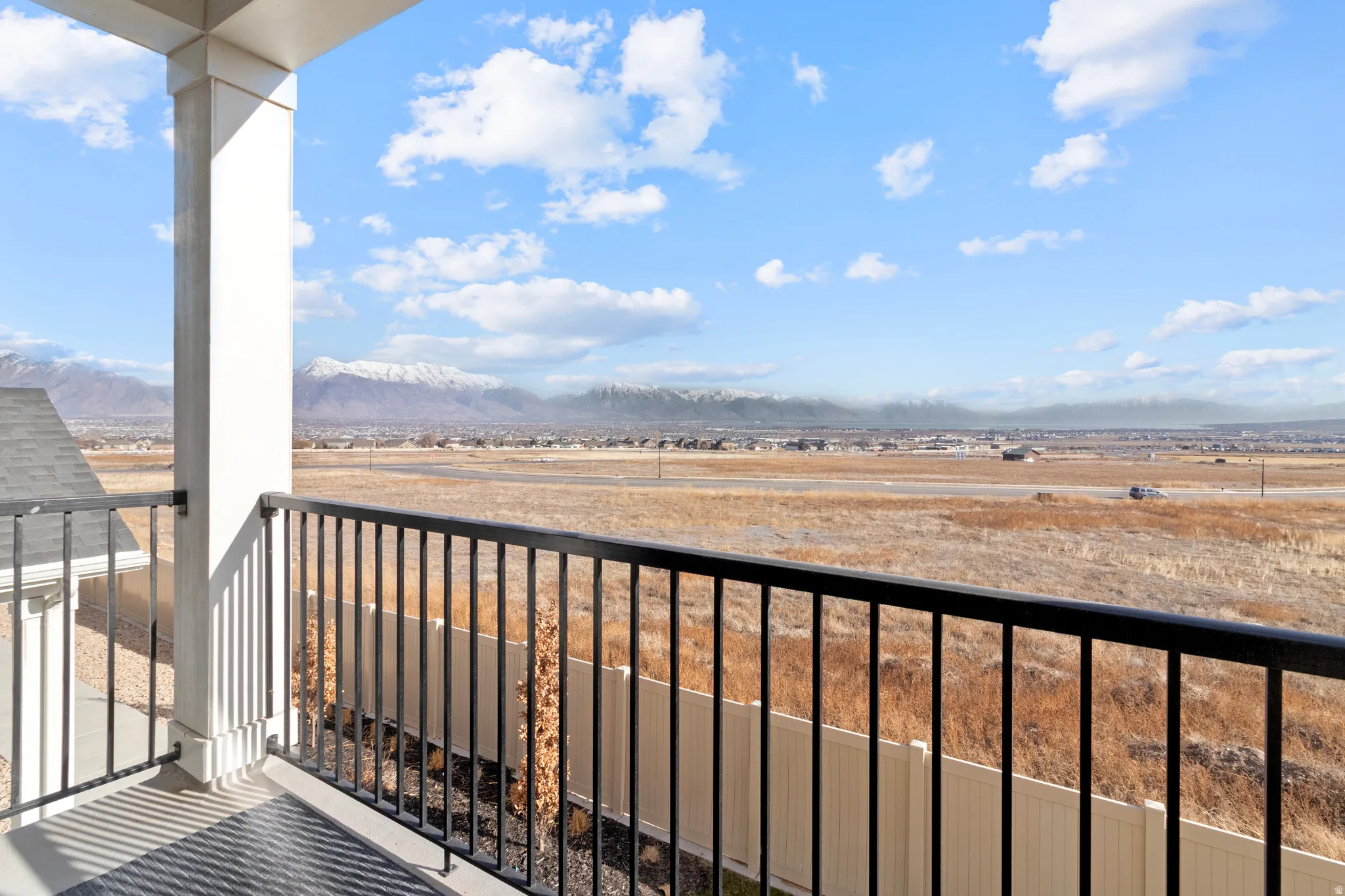 Spacious balcony featuring a black metal railing and a prominent white column