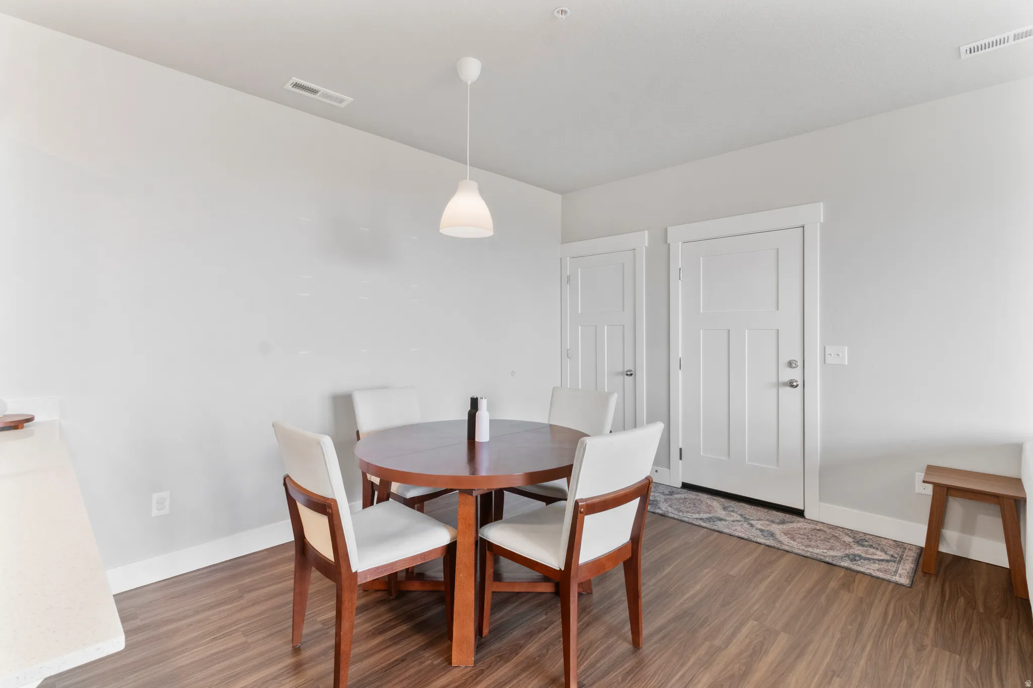 Wood-finish flooring, white trim, and a contemporary pendant light fixture
