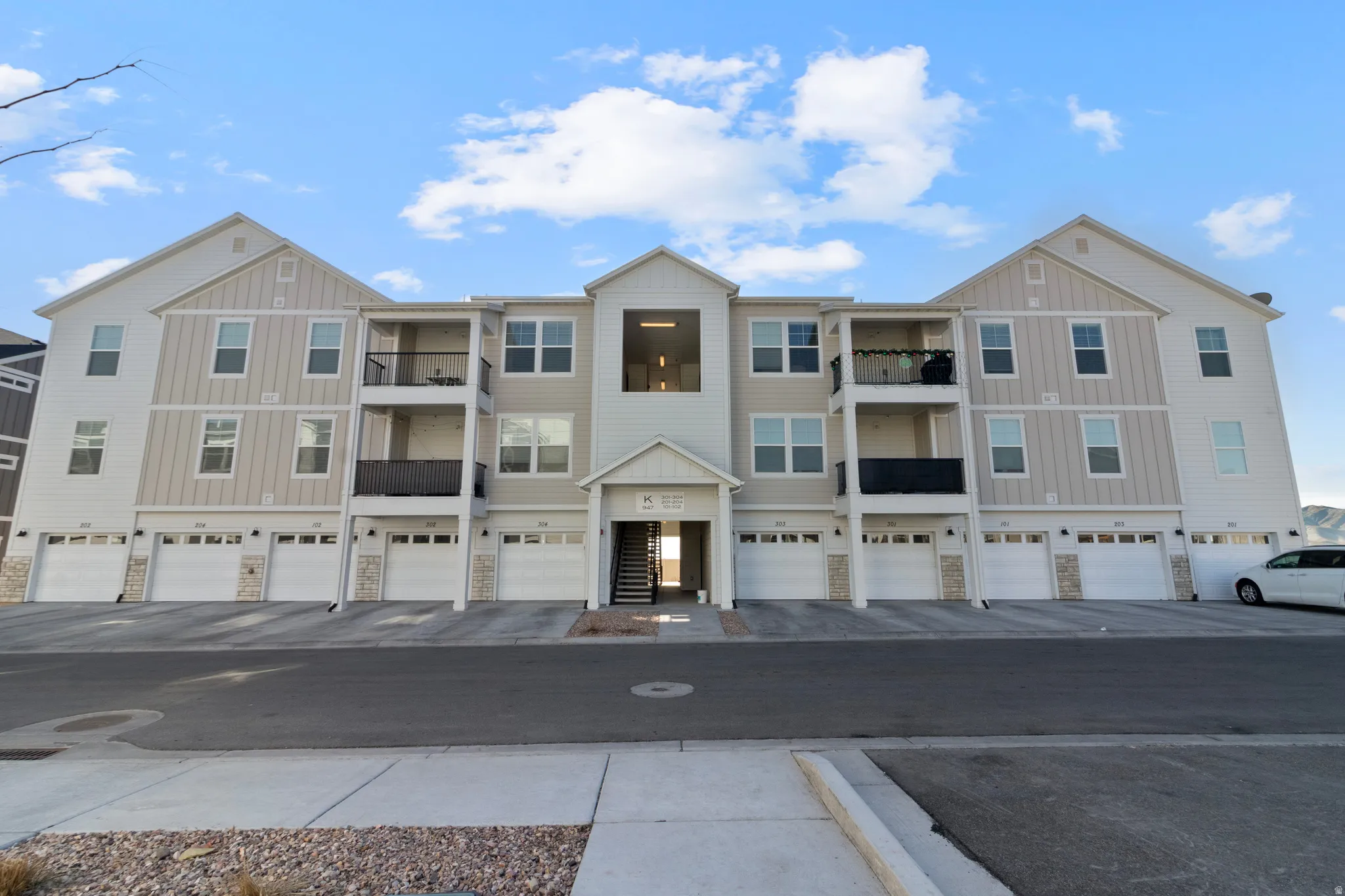 Multi-level building with individual garage bays, stone veneer accents, and private balconies