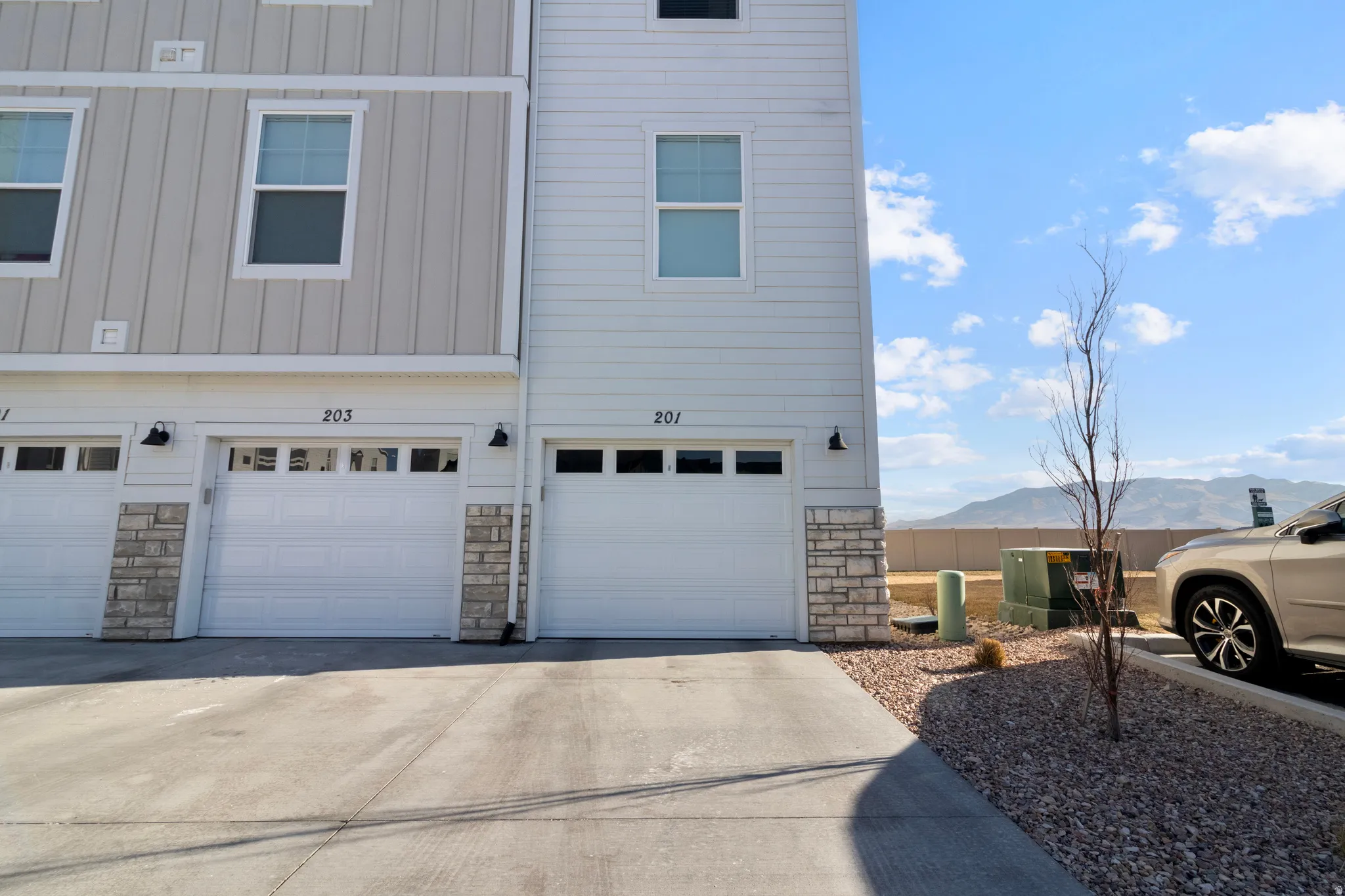 Multistory exterior featuring white siding and stone accents