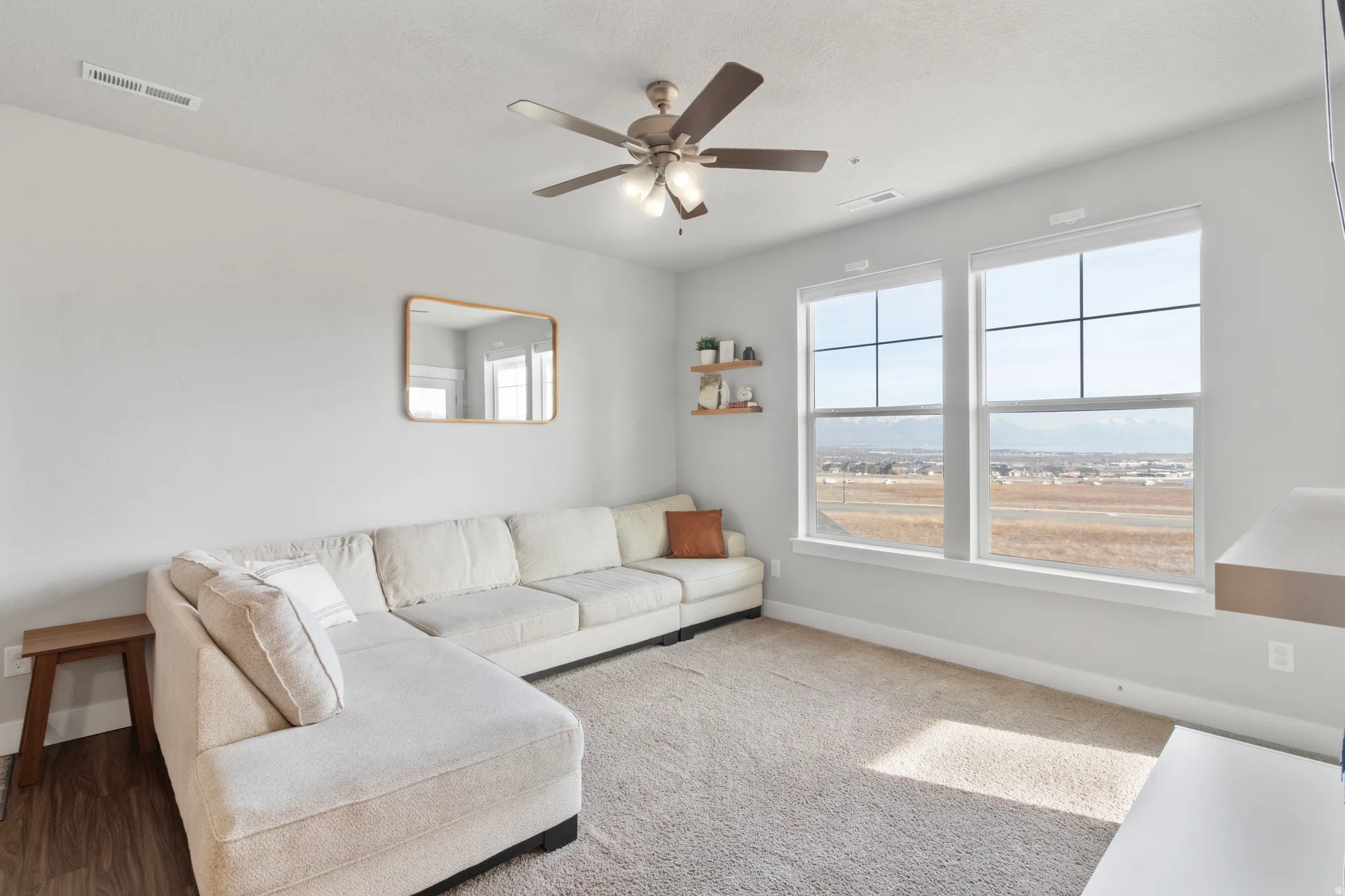 High ceilings with a ceiling fan, two large windows, and wall-mounted shelving