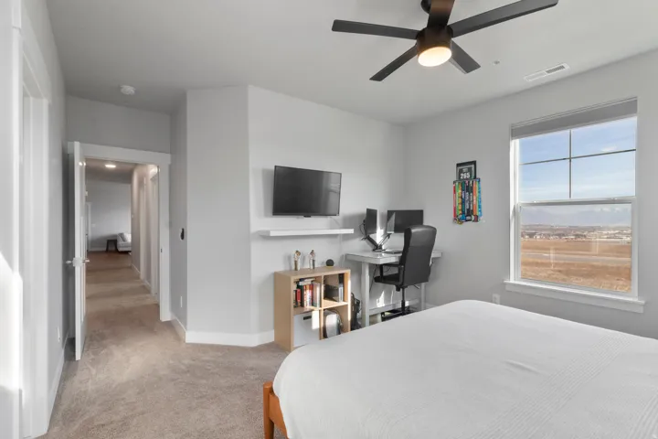 Bright room with large window, ceiling fan, and light-colored carpet