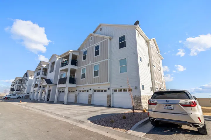 Multi-story exterior with horizontal and vertical siding, stone accents, multiple balconies with black railings, and individual garage doors