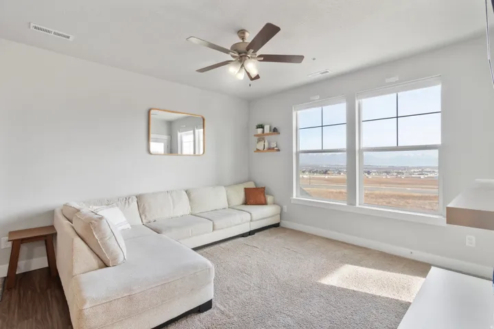 High ceilings with a ceiling fan, two large windows, and wall-mounted shelving