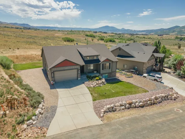 Modern ranch-style home featuring a two-car garage, concrete driveway, and a front yard with manicured lawn and rock landscaping