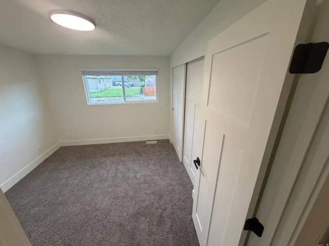 Neutral paint, plush carpeting, white trim, and a window with blinds