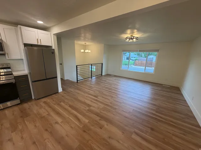 Wood-finish flooring throughout, stainless steel appliances, white cabinetry, quartz-finish countertops, and a contemporary railing system