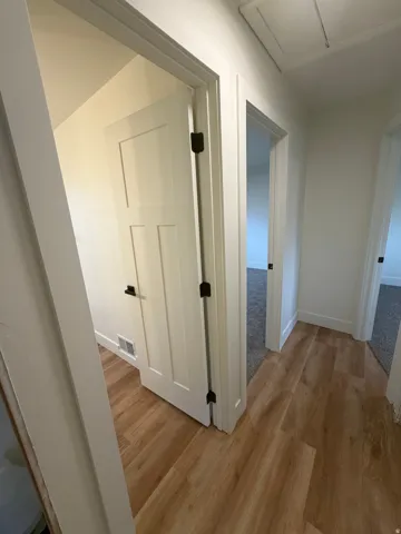 Wood-finish flooring, white paneled doors, matte black hardware, white trim, and light wall finishes