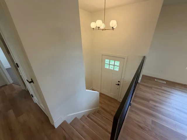 Entryway with wood-finish flooring, a modern chandelier, and a white paneled door with windowpanes