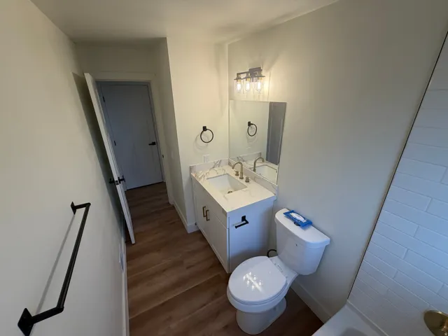 White vanity with gold-finish faucet, framed mirror, and three-light fixture