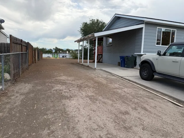 Exterior featuring a covered concrete patio, grey siding, and a partial wood fence
