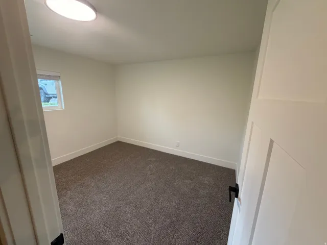 Neutral-toned carpet flooring, white walls, and a single window with a blind