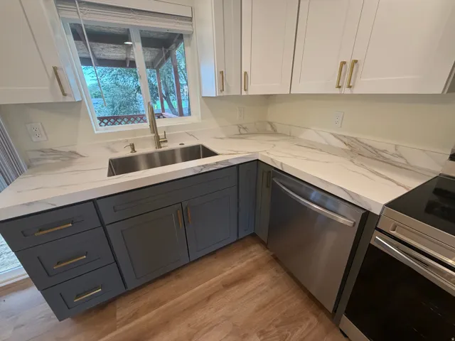 Modern kitchen featuring a two-tone cabinetry design with white upper cabinets and charcoal lower cabinets accented with brass hardware
