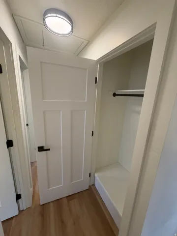 Wood-finish flooring with white trim and flat panel doors