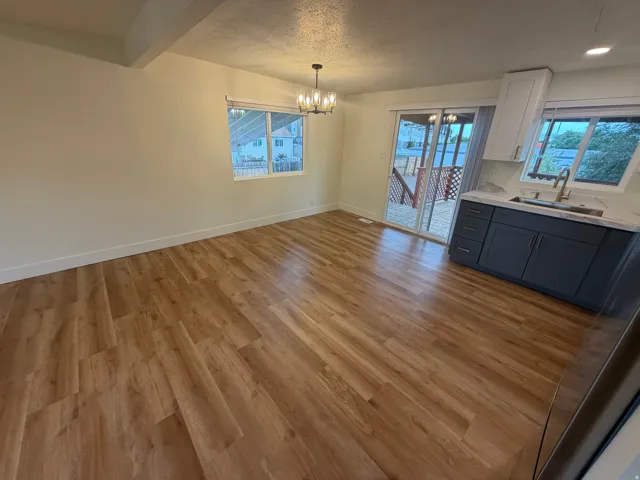 Open-concept living and kitchen area featuring wood-finish flooring throughout, recessed ceiling lighting, and custom dark cabinetry with integrated countertop workspace