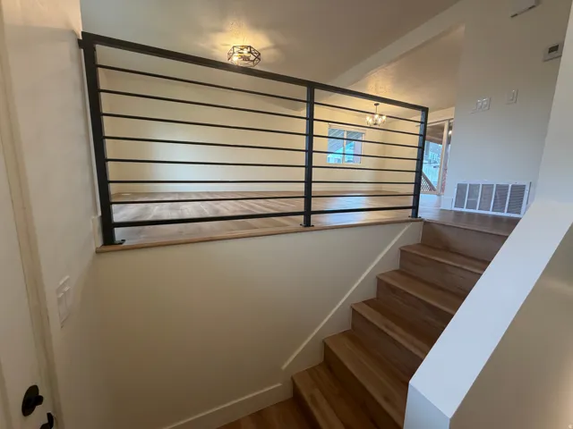 Staircase with wood-finish treads and risers, complemented by a contemporary metal horizontal-bar railing