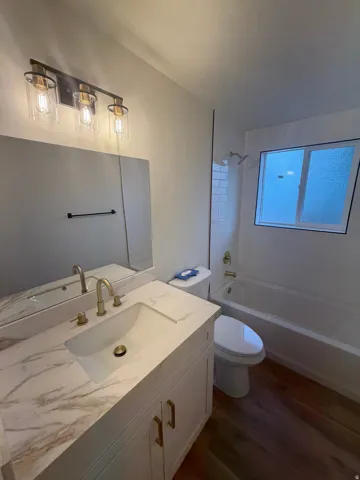 White vanity with gold-finish hardware, integrated sink, and patterned countertop