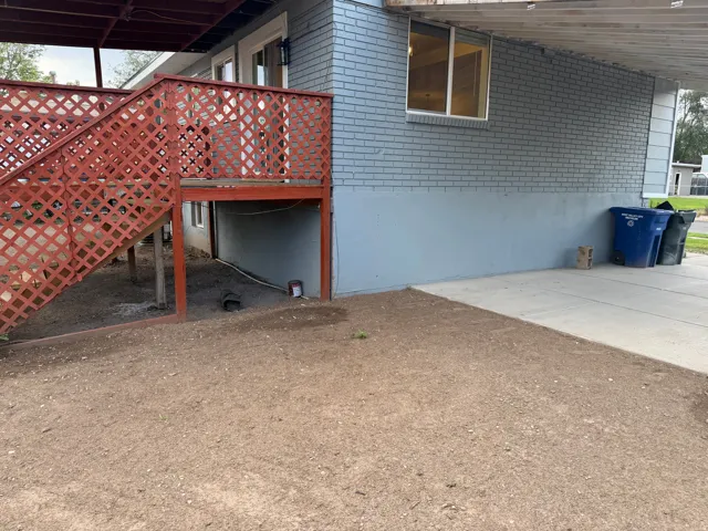 Red-stained wood deck with lattice railing, exterior brick siding, and concrete patio