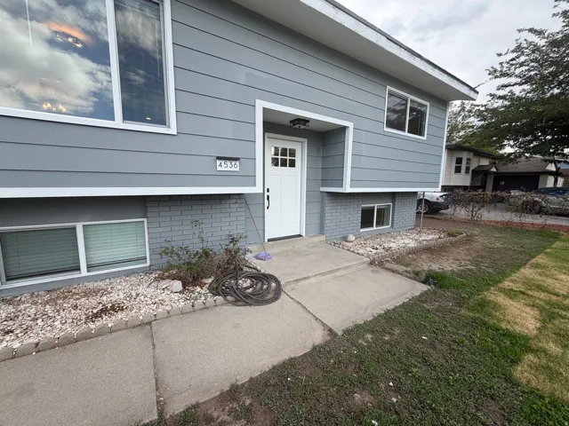 Grey horizontal siding with white trim, a white front door, and a concrete pathway