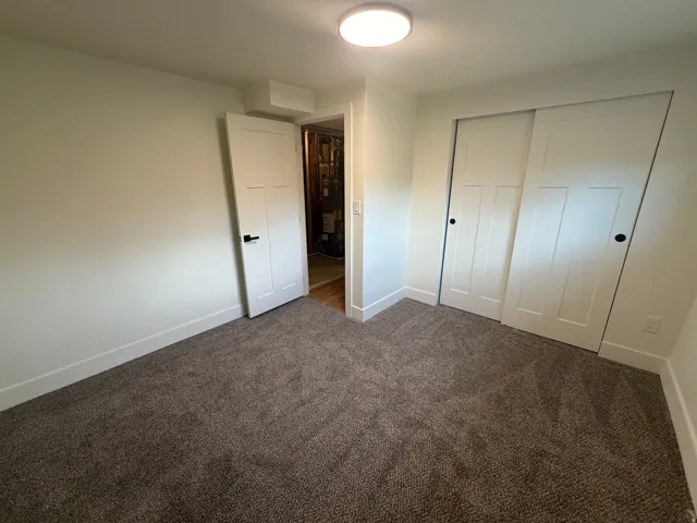 Neutral tone wall color, plush carpet flooring, white trim, recessed lighting, and a closet with sliding doors