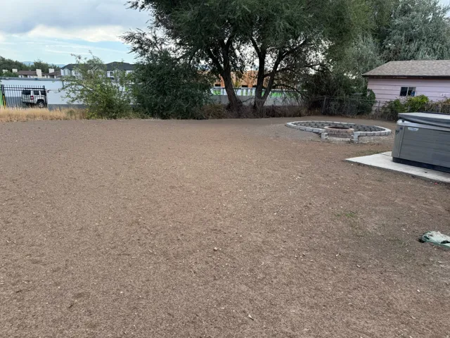 Expansive outdoor space featuring a paved fire pit area and mature trees