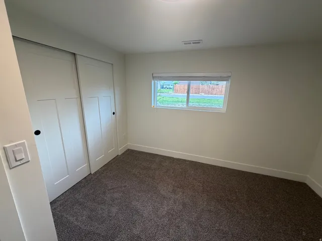Carpeted room with white walls, a white sliding closet door, and a white window frame