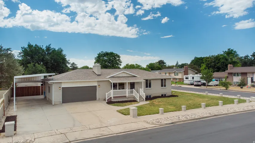 Single-story residence featuring a covered carport, attached garage, and a welcoming front porch with white railings